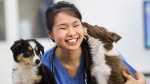 A woman smiling with two dogs on her lap.