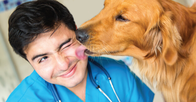 A man with his tongue out licking the nose of a dog.