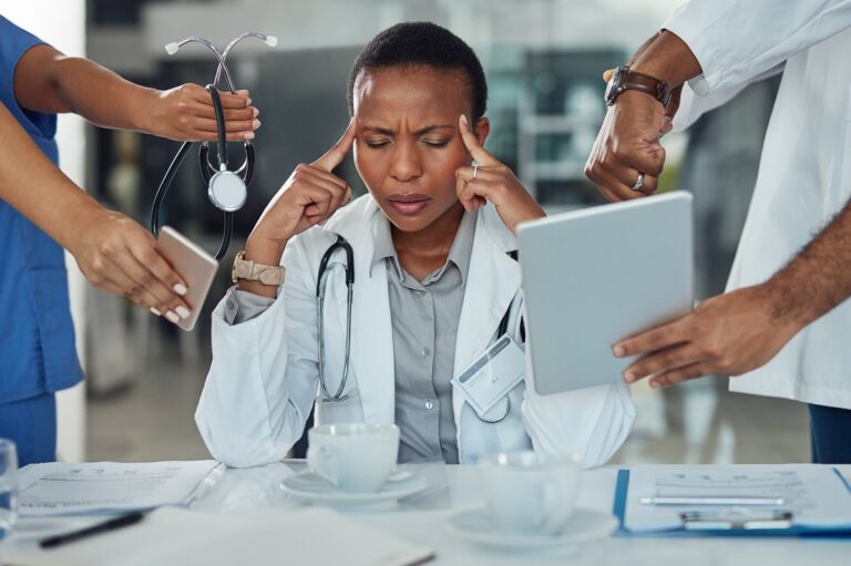 A doctor is surrounded by many people at the table.