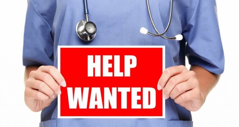 A nurse holding a sign that says "Help Wanted".