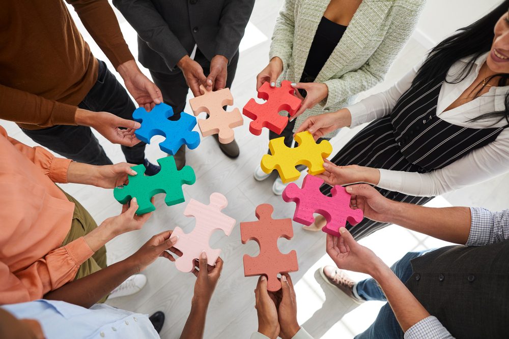 Diverse group holding colorful puzzle pieces.