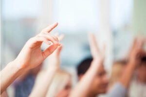 Hand raised in a classroom of students.