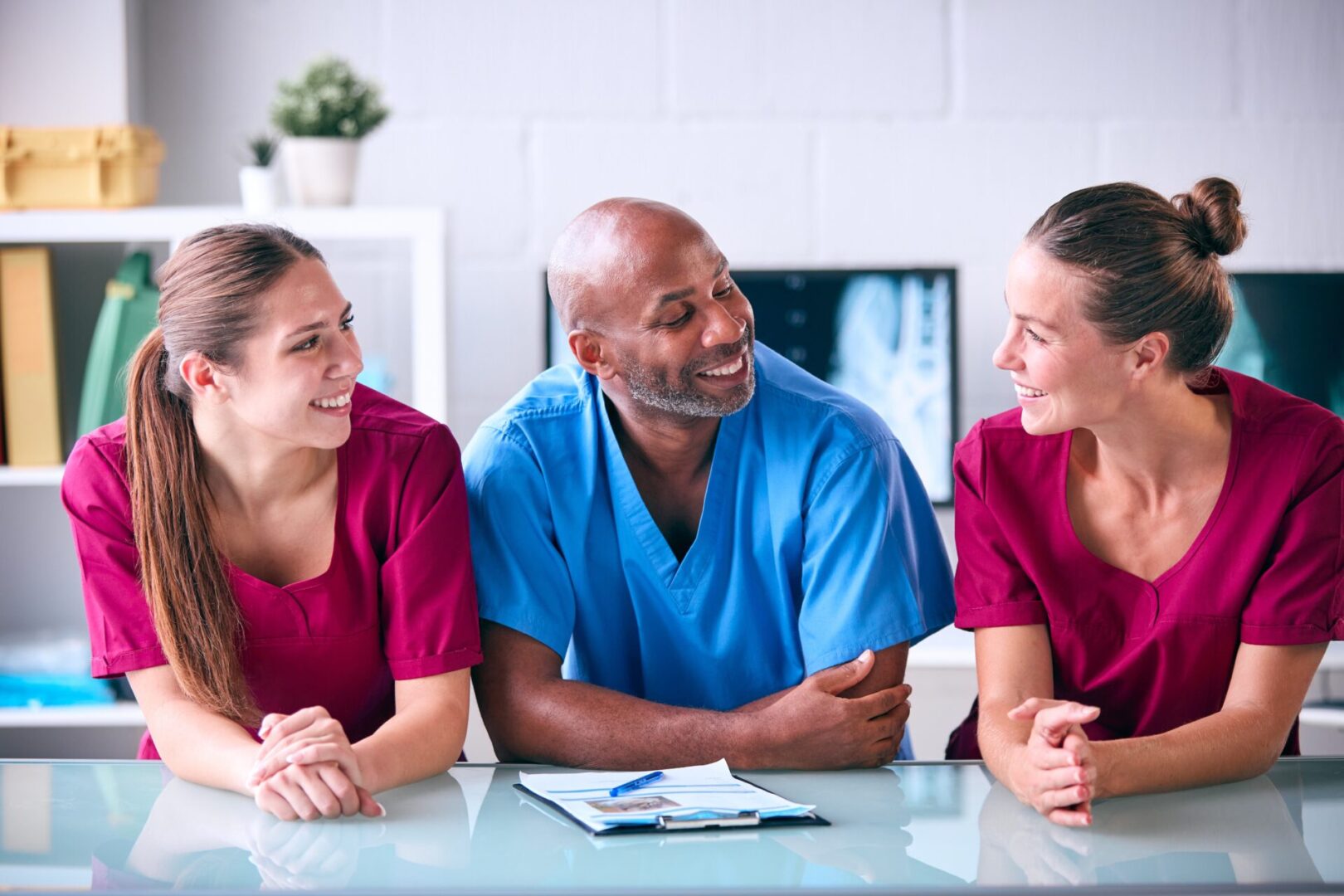 Portrait,Of,Male,And,Female,Veterinary,Team,In,Surgery Medical professionals smiling and conversing at table.